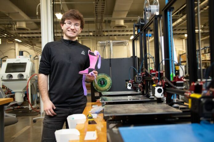 Peyton Deaton, junior Chemical Engineering student, is shown with the leg brace he designed and 3D printed.