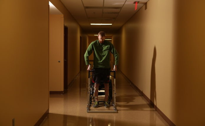 Spinal cord therapy research participant Jeff Marquis stands during therapy. Photo by Jessica Ebelhar.