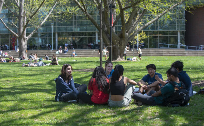 Students engage in conversation outside on the lawn at UofL's Belknap Campus.