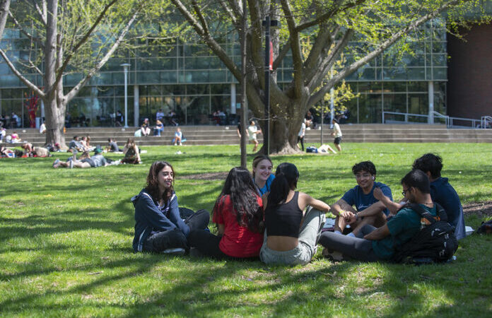 Students engage in conversation outside on the lawn at UofL's Belknap Campus.