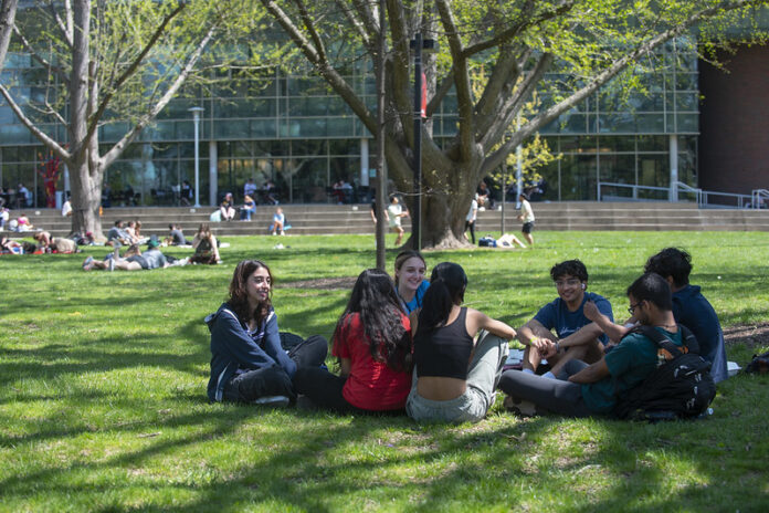 Students engage in conversation outside on the lawn at UofL's Belknap Campus.